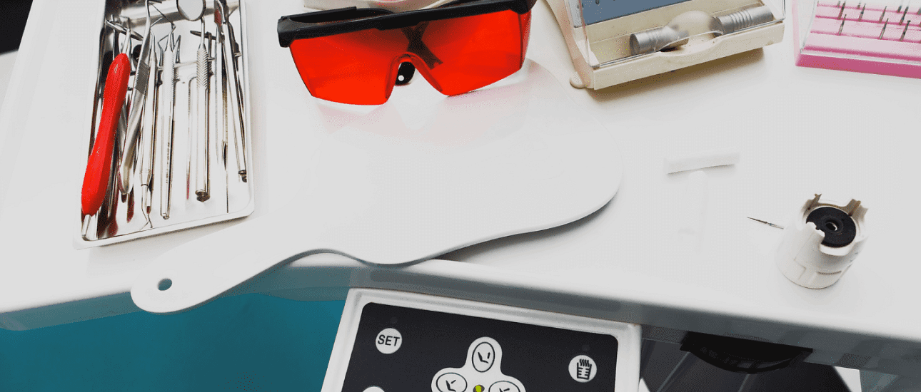 In the dental office at Holt Orthodontics in Twinsburg, OH, a white tray holds dental instruments, metal braces, red protective glasses, a handheld mirror, and other equipment.