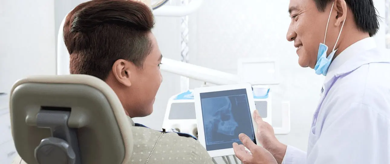 At Holt Orthodontics in Twinsburg, OH, a dentist discusses potential jaw surgery with a patient by reviewing a dental X-ray together on a tablet.