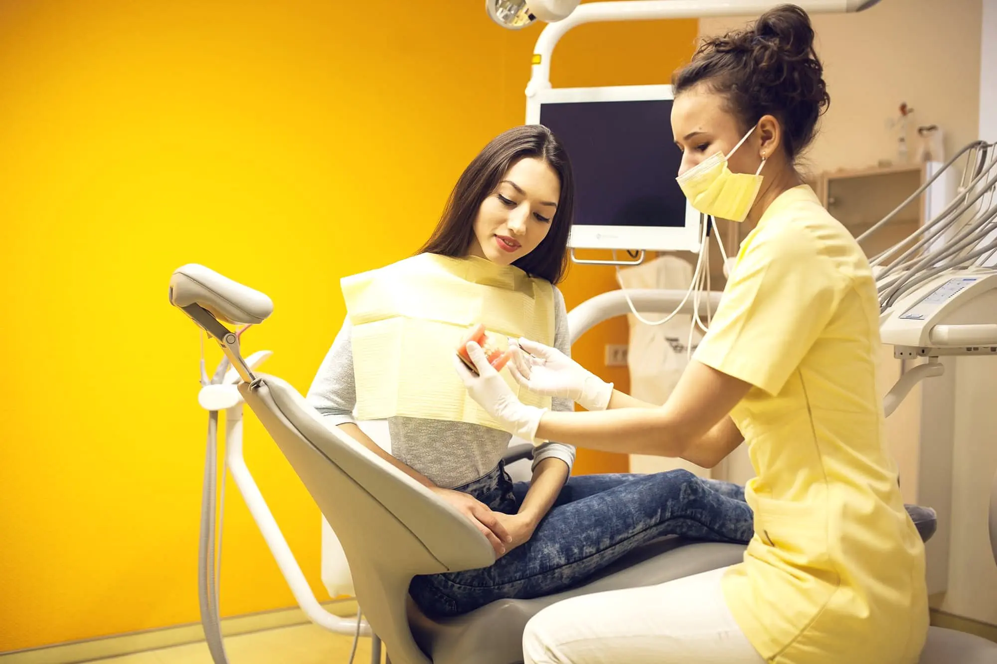 At Holt Orthodontics in Twinsburg, OH, a dental professional in yellow scrubs discusses orthodontic insurance plans with a female patient to ensure comprehensive care before treatment.