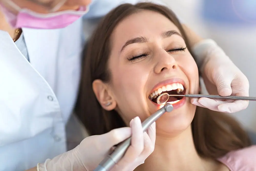 At Holt Orthodontics in Twinsburg, OH, a dentist examines a woman’s teeth with dental instruments to check for signs of tongue thrust as she sits in the chair with her mouth open.