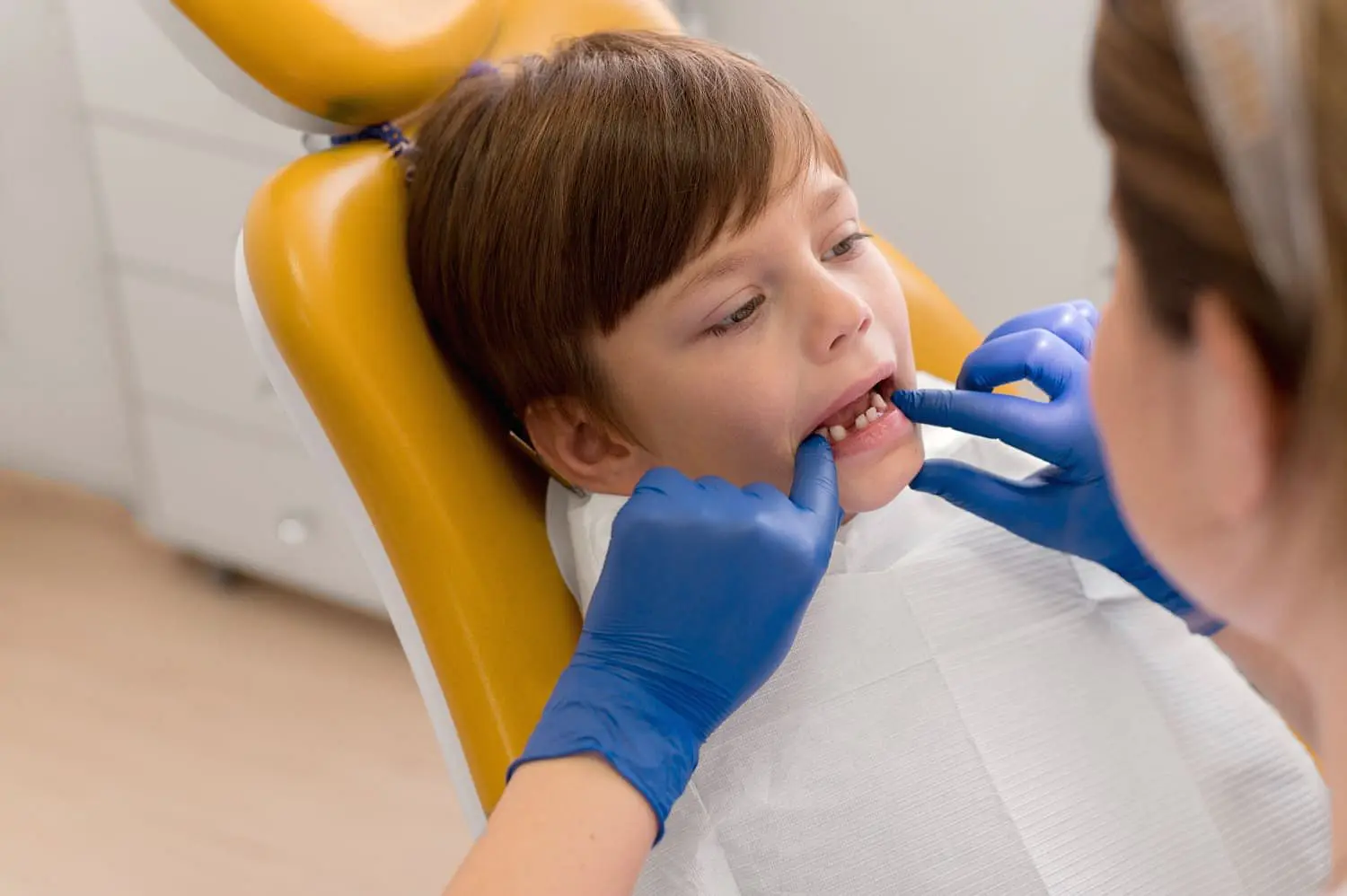 At Holt Orthodontics in Twinsburg, OH, a dentist wearing blue gloves examines a child's teeth and discusses possible orthodontic appliances for better dental alignment.