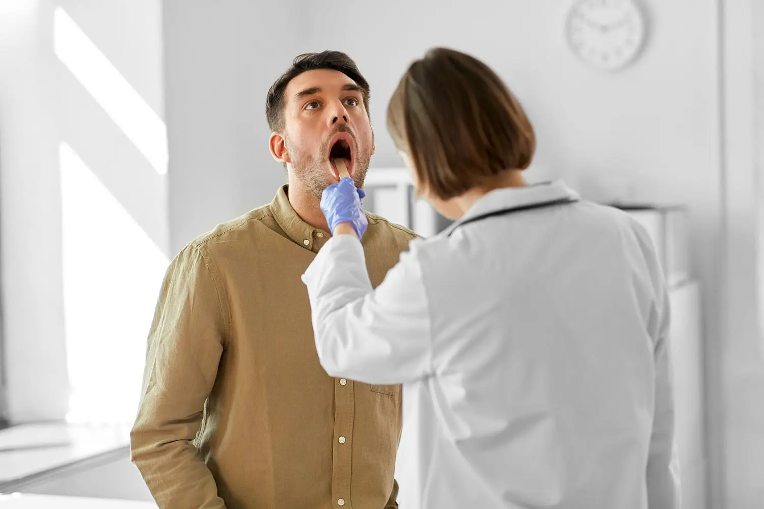 At Holt Orthodontics in Twinsburg, OH, a healthcare professional in a white coat examines a seated man's open mouth to check for signs of tongue thrust.