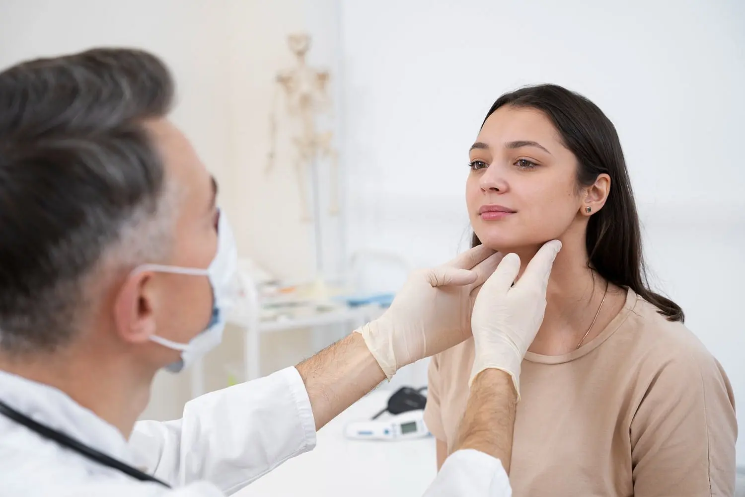 At Holt Orthodontics in Twinsburg, OH, a doctor wearing gloves examines a young woman's neck—likely evaluating her recovery after jaw surgery—as she sits calmly in the medical office.