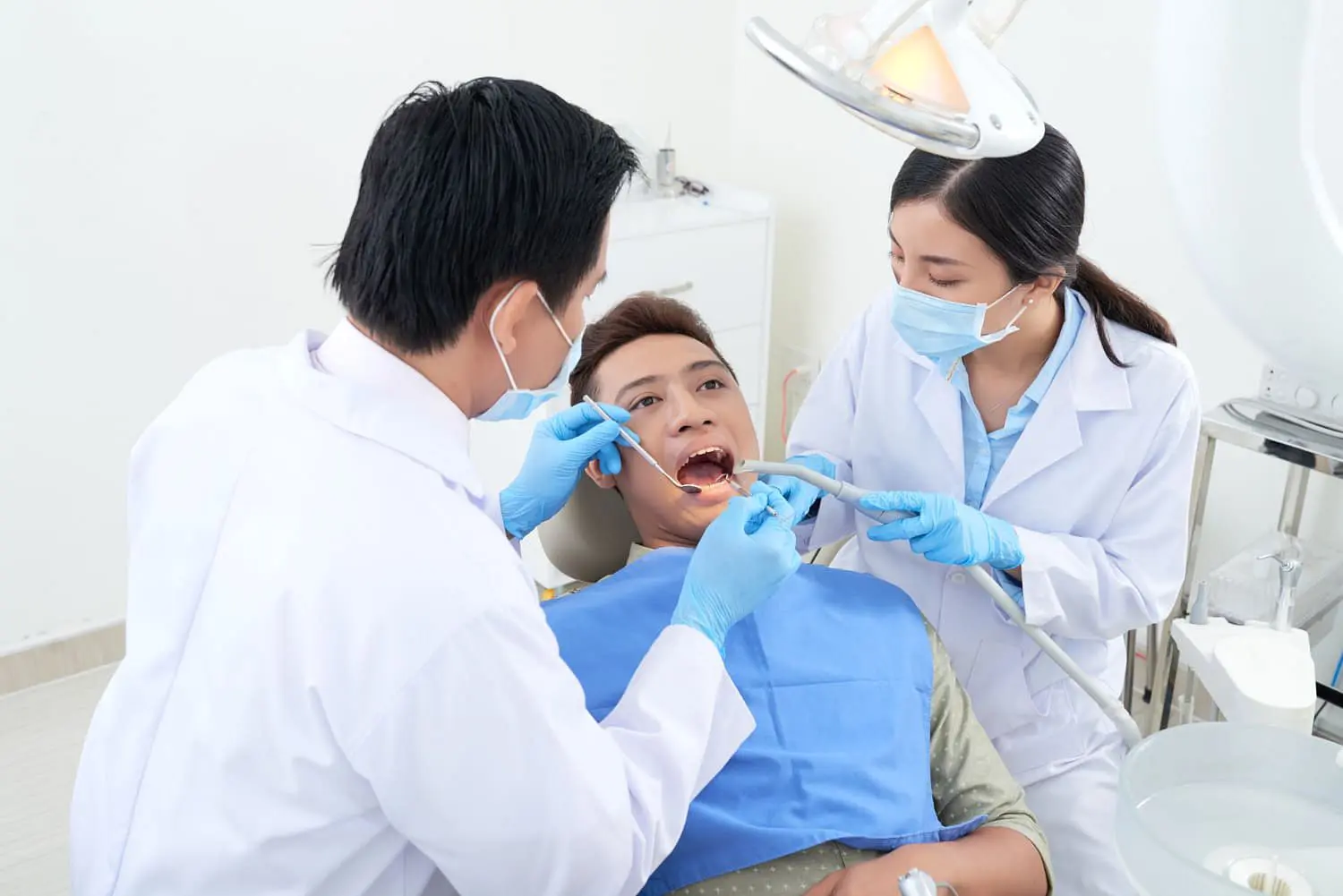 At Holt Orthodontics in Twinsburg, OH, a dentist and dental assistant—both masked and gloved—examine a patient's teeth for tongue thrust using dental tools in a well-lit clinic.