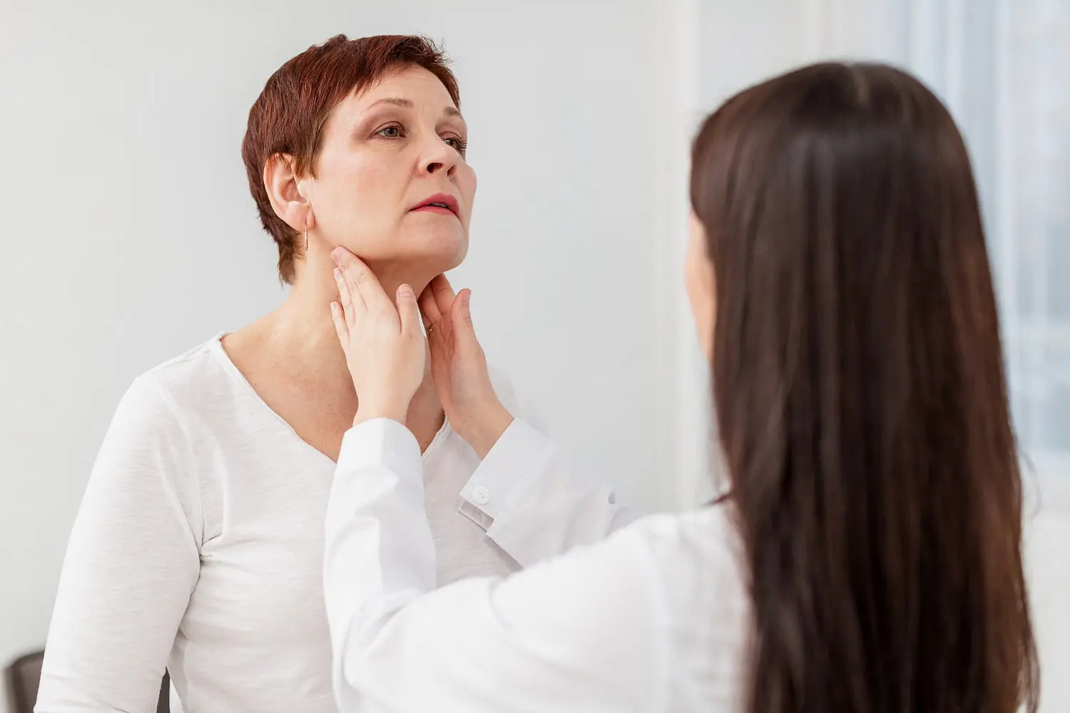At Holt Orthodontics in Twinsburg, OH, a healthcare professional carefully examines a woman's neck to assess her throat for conditions that may need evaluation before or after jaw surgery.