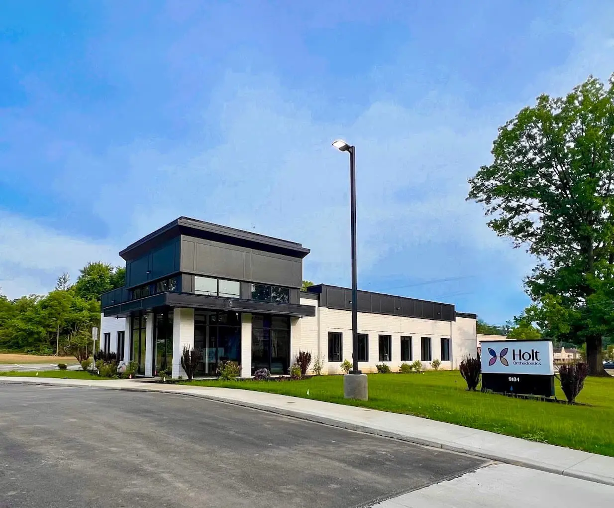 Located in Twinsburg, OH, Holt Orthodontics features a modern white and black commercial building with large windows, lush greenery, and a prominent "Holt Orthodontics Expert" sign near the entrance. We provide to place a teeth retainer for patient in Twinsburg, OH.