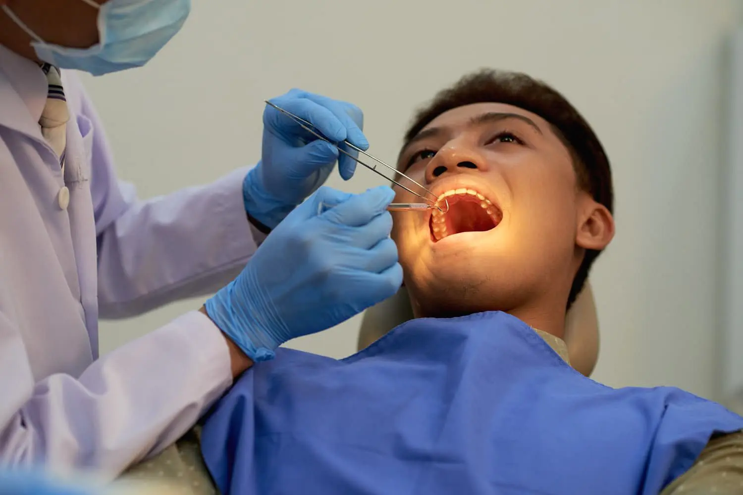 At Holt Orthodontics in Twinsburg, OH, a dentist wearing gloves uses dental tools to examine a patient’s mouth for issues such as an underbite while the patient sits in the dental chair.