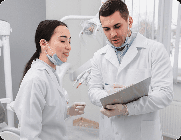 At Holt Orthodontics in Twinsburg, OH, two dental professionals in lab coats and masks discuss adult orthodontics as one makes notes on a clipboard in a modern office setting.