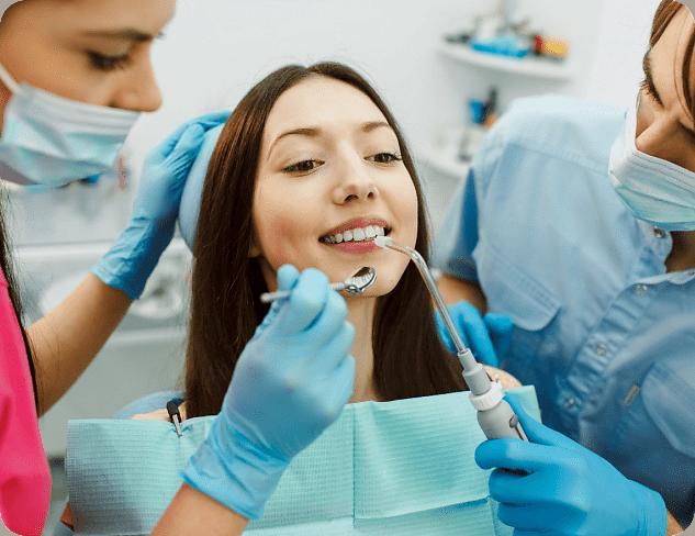 At Holt Orthodontics in Twinsburg, OH, two dentists with masks and gloves perform an adult orthodontics procedure on a woman seated in a dental chair.