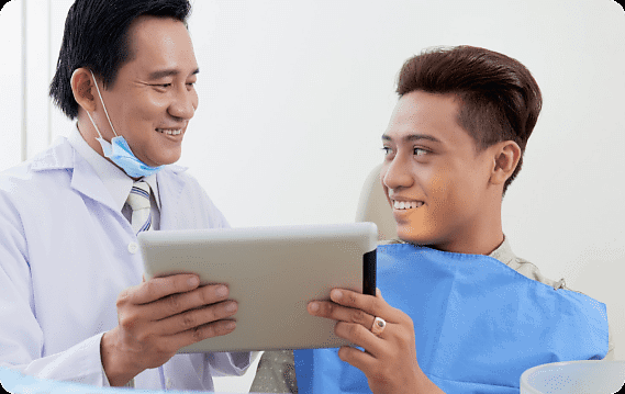 At Holt Orthodontics in Twinsburg, OH, a dentist discusses dental care and potential jaw surgery options with a smiling patient using a tablet.