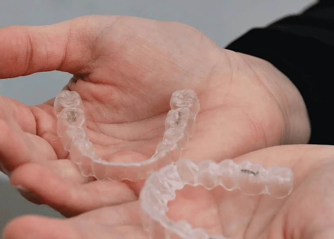 A person examines two clear dental aligners, exploring the advantages of an Invisalign Payment Plan with Holt Orthodontics in Twinsburg, OH.