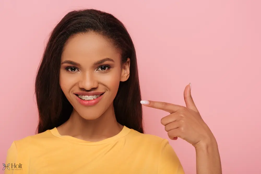 smiling african american girl pointing finger metal braces her teeth - Braces for Overbite in Twinsburg, OH. 