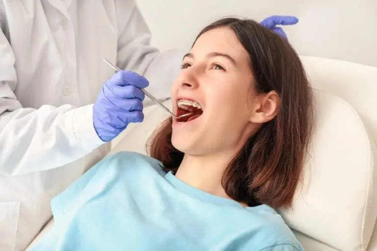 A gloved dentist at Holt Orthodontics examines a smiling teen with braces, advising on how to fix overbite in Twinsburg, OH.