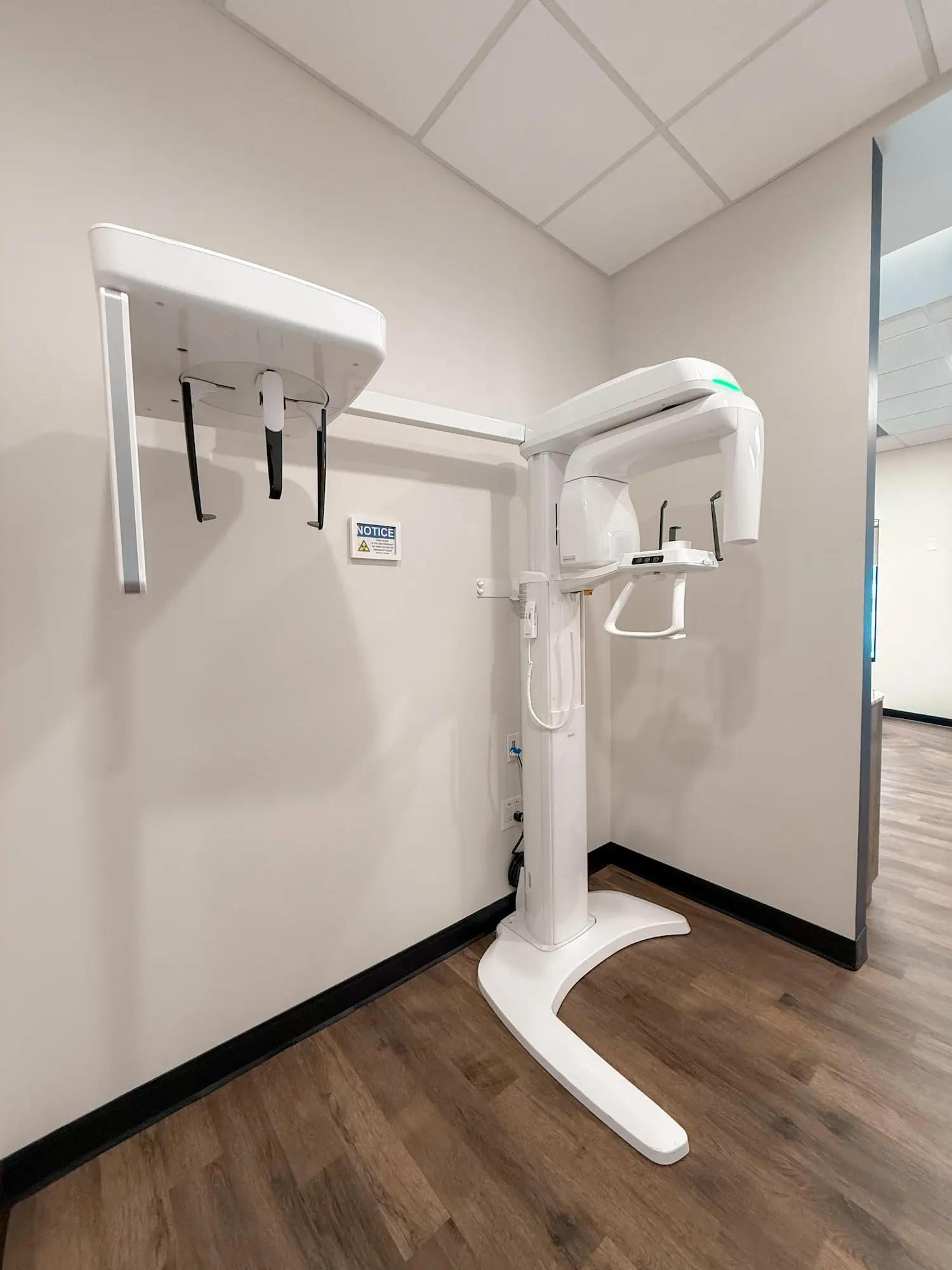 A dental panoramic X-ray machine at Holt Orthodontics in Twinsburg, OH stands in a room with white walls and wood flooring.