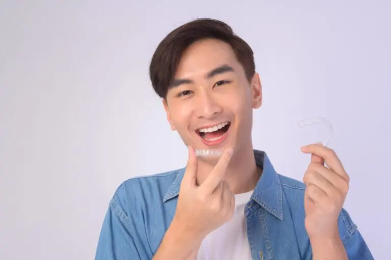 young smiling man holding invisalign clear aligners white background studio dental - How Does Invisalign Work in Twinsburg, OH