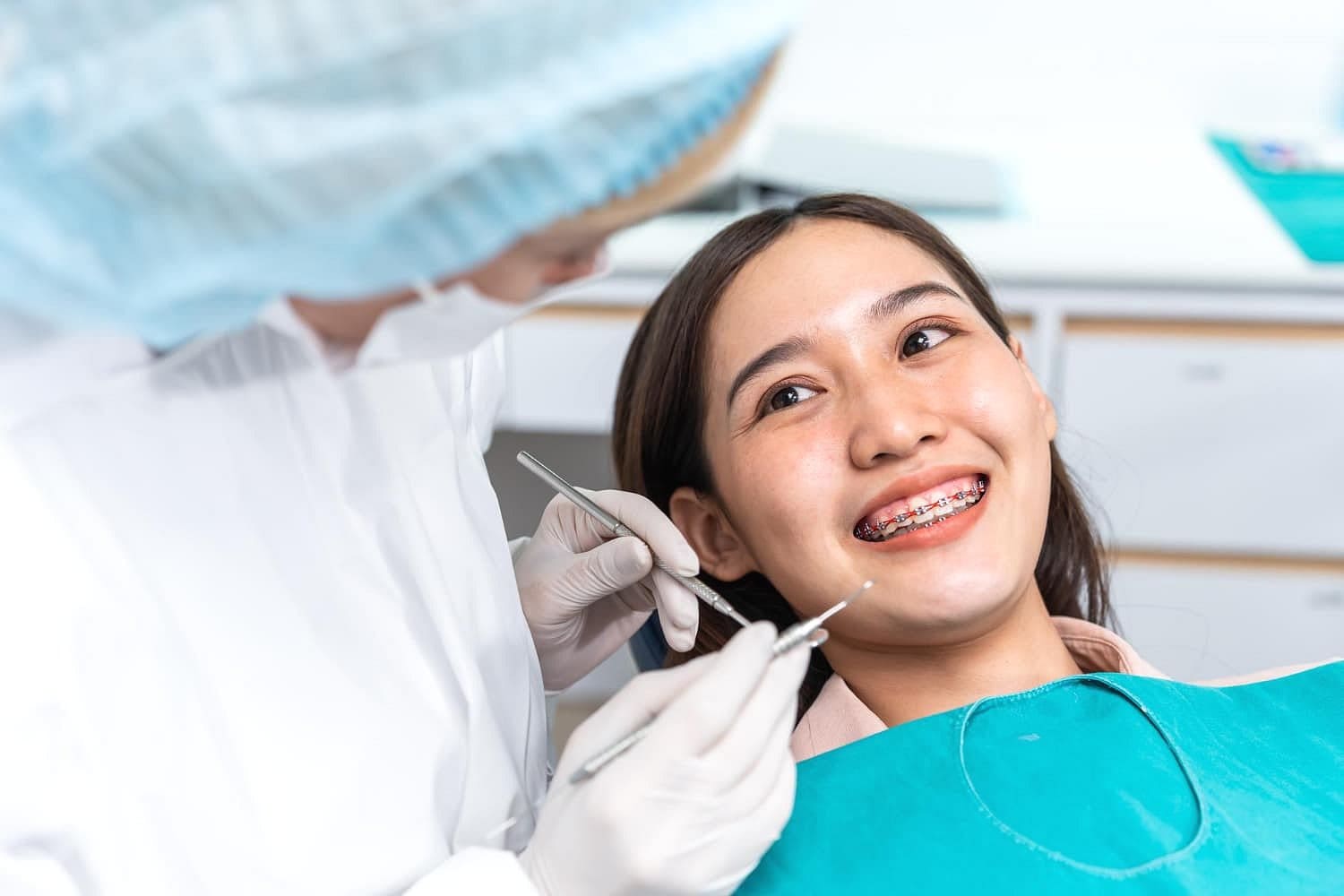 At Holt Orthodontics in Twinsburg, OH, a dentist uses dental tools to check a smiling patient with braces for signs of tongue thrust in a brightly lit clinic.