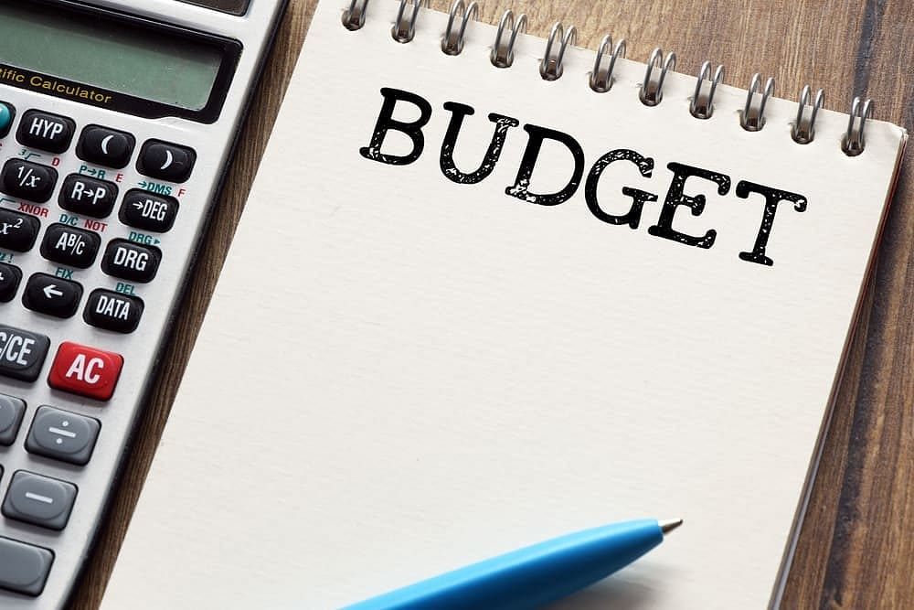 On a wooden surface at Holt Orthodontics in Twinsburg, OH, a calculator, blue pen, and notepad labeled "BUDGET" are set out to help you plan your Braces Payment Plan.