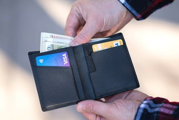 At Holt Orthodontics in Twinsburg, OH, an individual holds an open black wallet with cash and two credit cards—prepared to manage expenses such as an Invisalign Payment Plan.