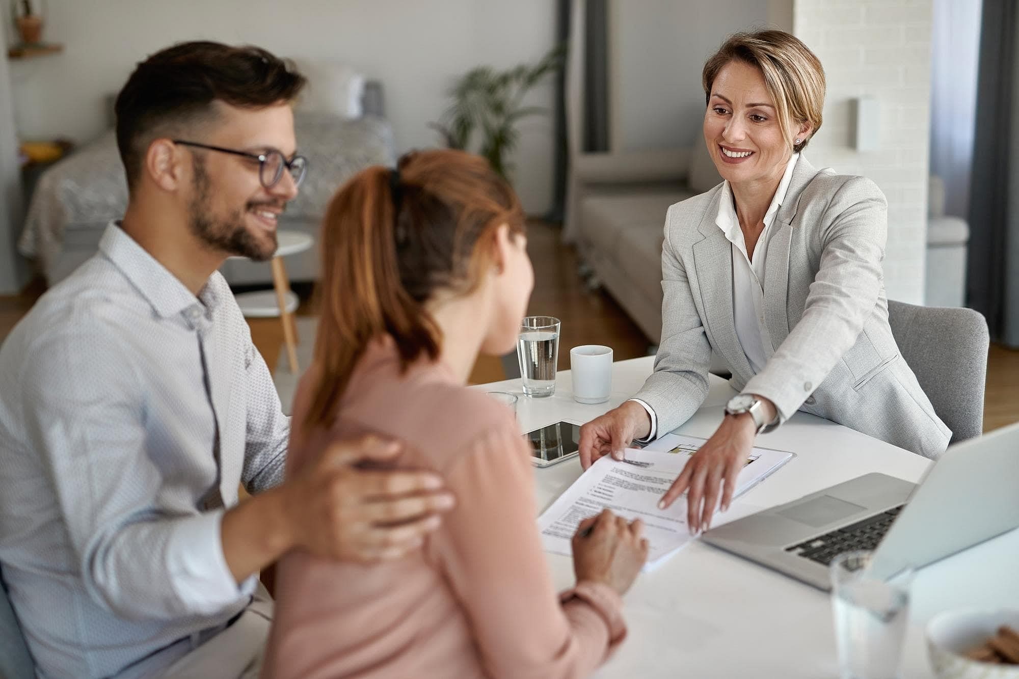 At Holt Orthodontics in Twinsburg, OH, a woman in a suit presents Invisalign Payment Plan documents to a smiling couple during a consultation in a home or office setting.