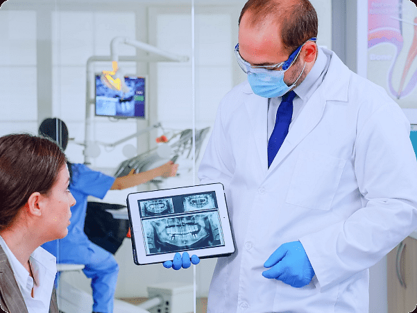 At Holt Orthodontics in Twinsburg, OH, a dentist reviews a dental X-ray on a tablet with a patient, explaining possible jaw surgery options.