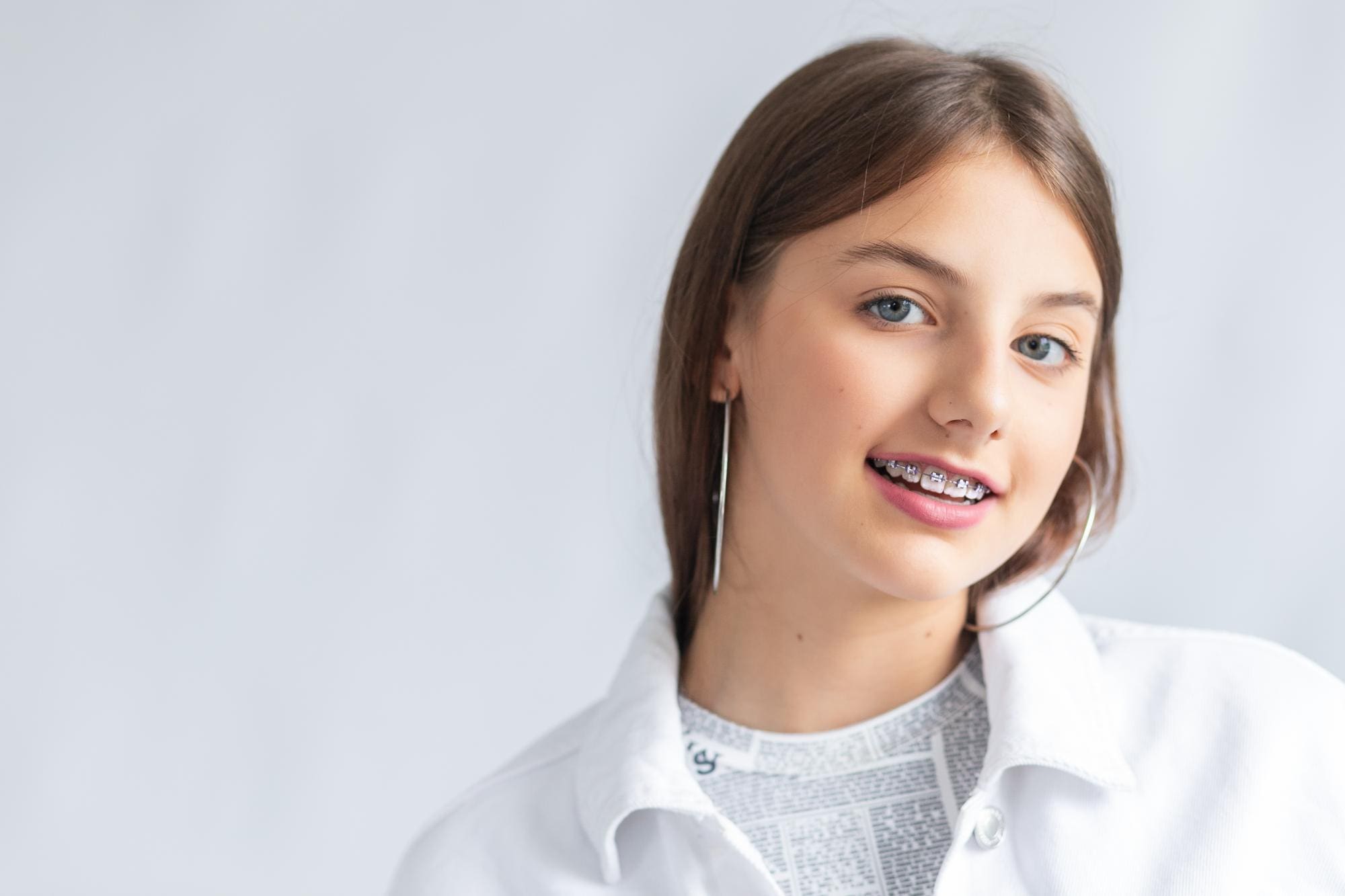 A smiling woman with long dark hair and braces, represents best Children’s Orthodontist at Holt Orthodontics in Twinsburg, OH.