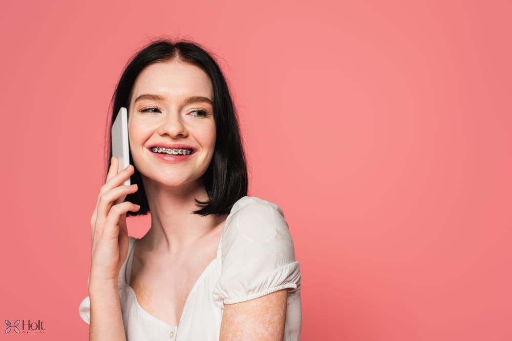 smiling woman with metal braces vitiligo talking mobile phone - Braces for Overbite in Twinsburg, OH. 